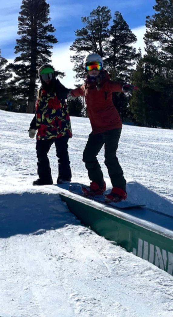 Coach helping a snowboarder learn how to ride a box