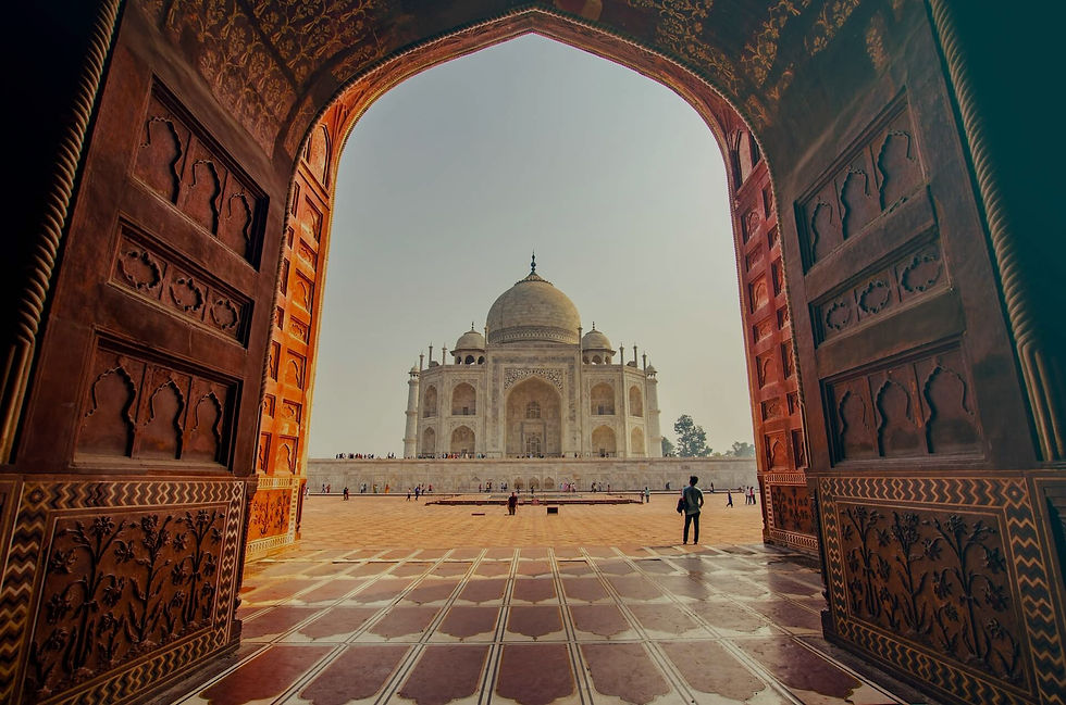 A large white building with a prominent dome, surrounded by people in front of it. The scene is outdoors under a clear sky, showcasing the symmetry and historic nature of the landmark.