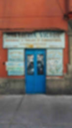 A blue double door with a sign for 'Sastrería Victor' on a wall, advertising tailoring services. 