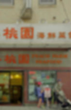 Peach Farm Seafood restaurant sign, with bright orange letters. Two girls stand outside talking.