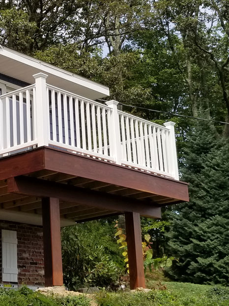 Raised wooden deck with white railing attached to a house