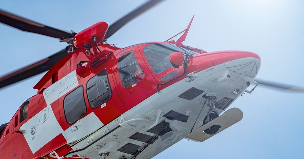 A close-up view of a red medical helicopter flying near snowy alpine terrain during a response operation.