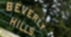 A close-up of the Beverly Hills sign placed on a metal structure in front of multiple different-sized trees.