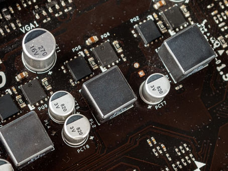 A brown motherboard holding silver capacitors, square chokes, black chips, and rows of tiny soldered parts.