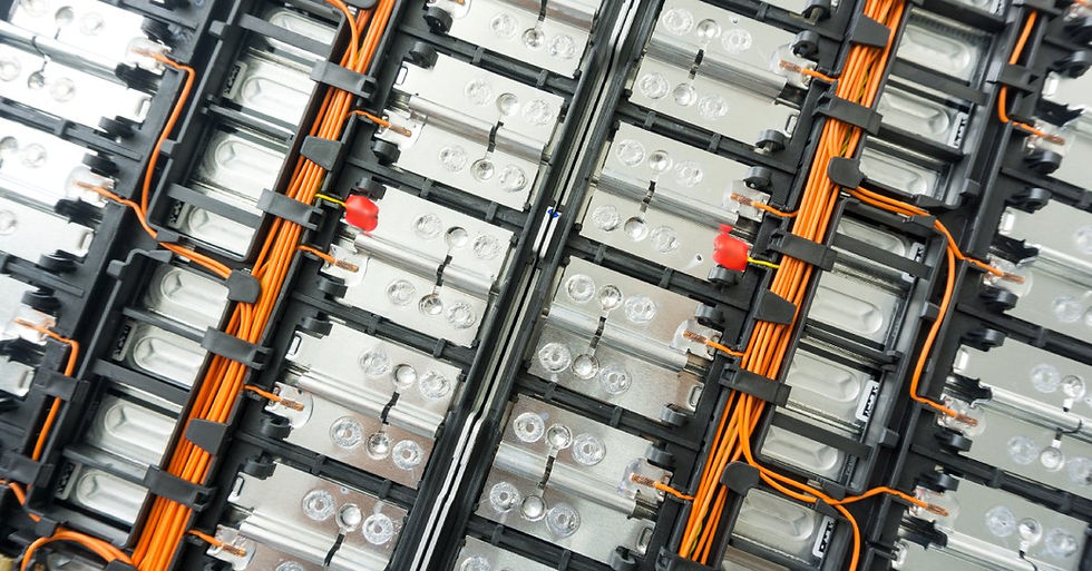 An electrical board with metal components and orange wires attached to the system. There are black clamps on the board.