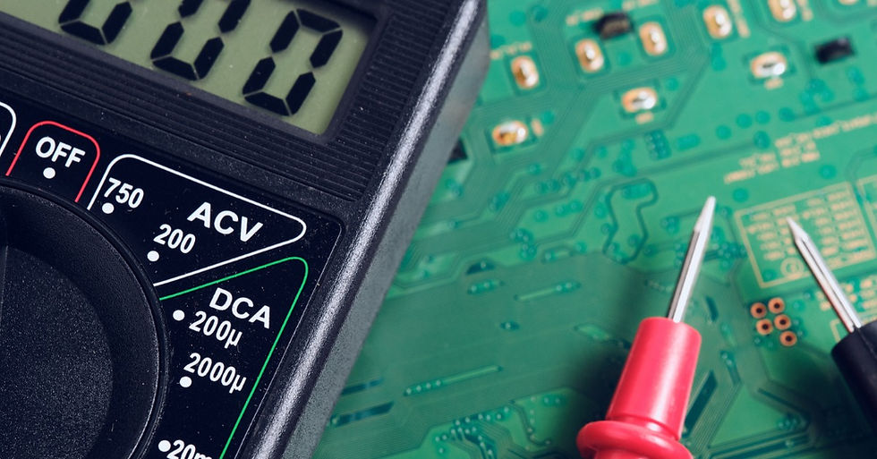 A black multimeter and red and black testing probes resting on a green circuit board with metal contact points.