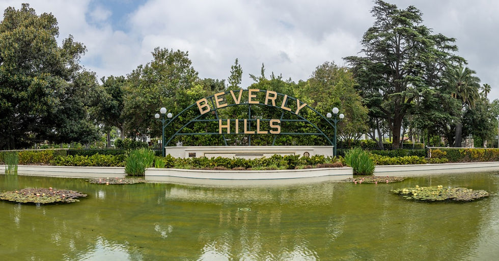 The “Beverly Hills” sign placed on a large metal structure in front of a large artificial lake surrounded by trees.