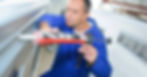 A mechanic applies sealant along the edge of an RV roof. He uses a caulking gun to ensure smooth, even application.