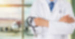 A person wearing a doctor's white coat stands with arms folded while holding a stethoscope. Behind him is the tarmac.
