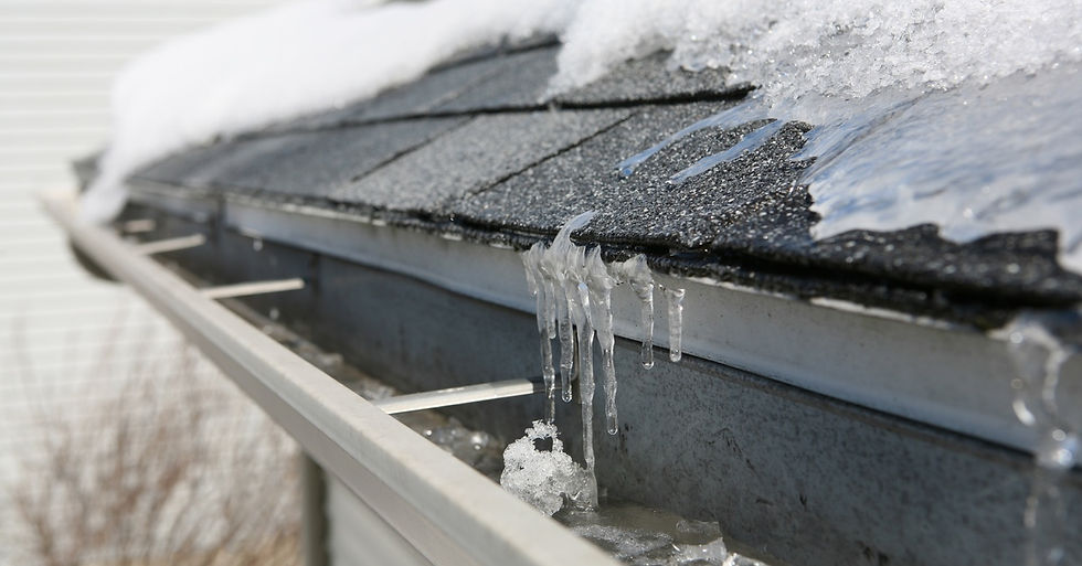 A black tiled roof covered in snow and ice. The ice is covering the gutters and creating a backup of ice and water.