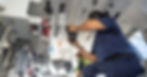 A professional wearing blue scrubs holds a headphone while surrounded by various medical devices in a helicopter.