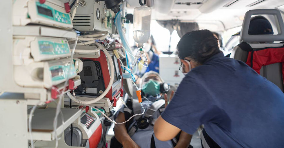A person leaning beside another person on a stretcher and medical devices inside a helicopter cabin.