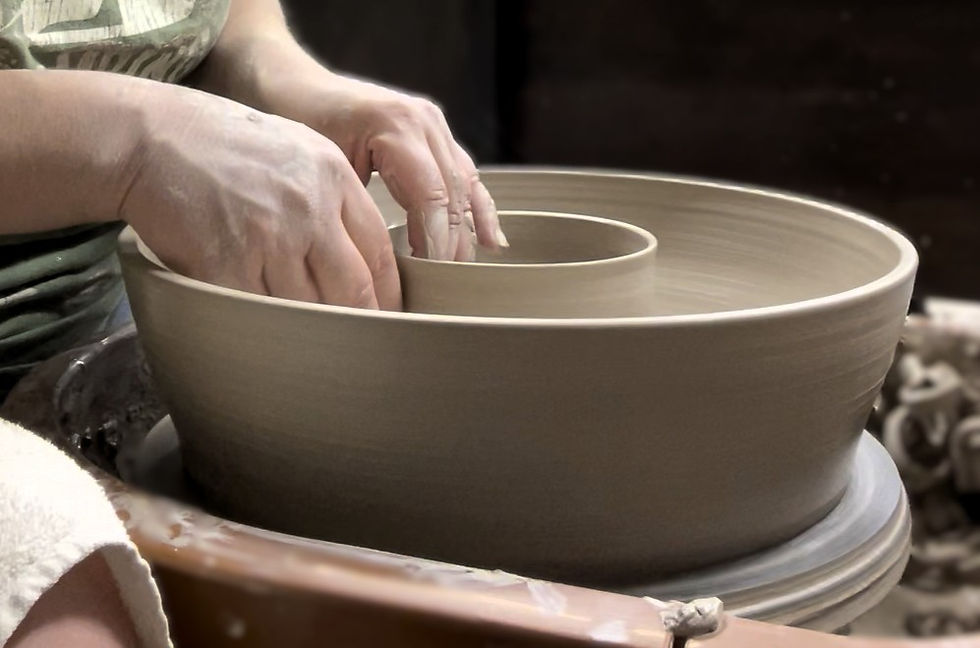 Eye-level view of a potter shaping a clay vase on a wheel