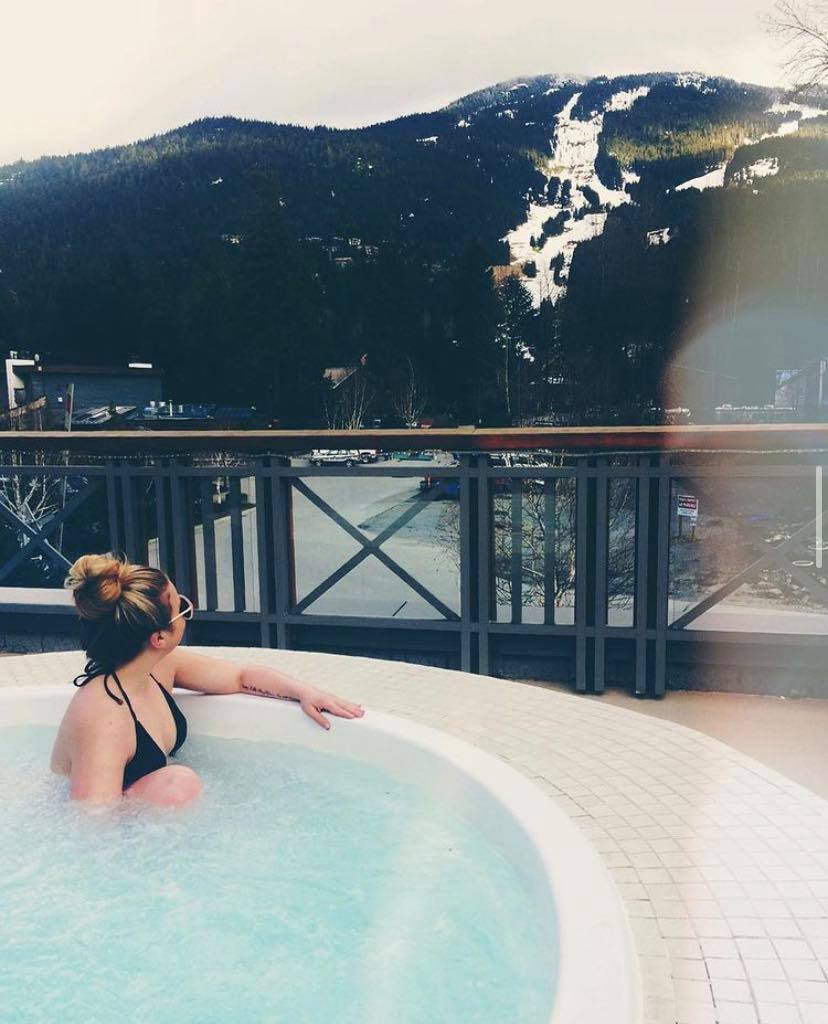 Girl, in steamy hot tub, looking out to beautiful mountain backdrop