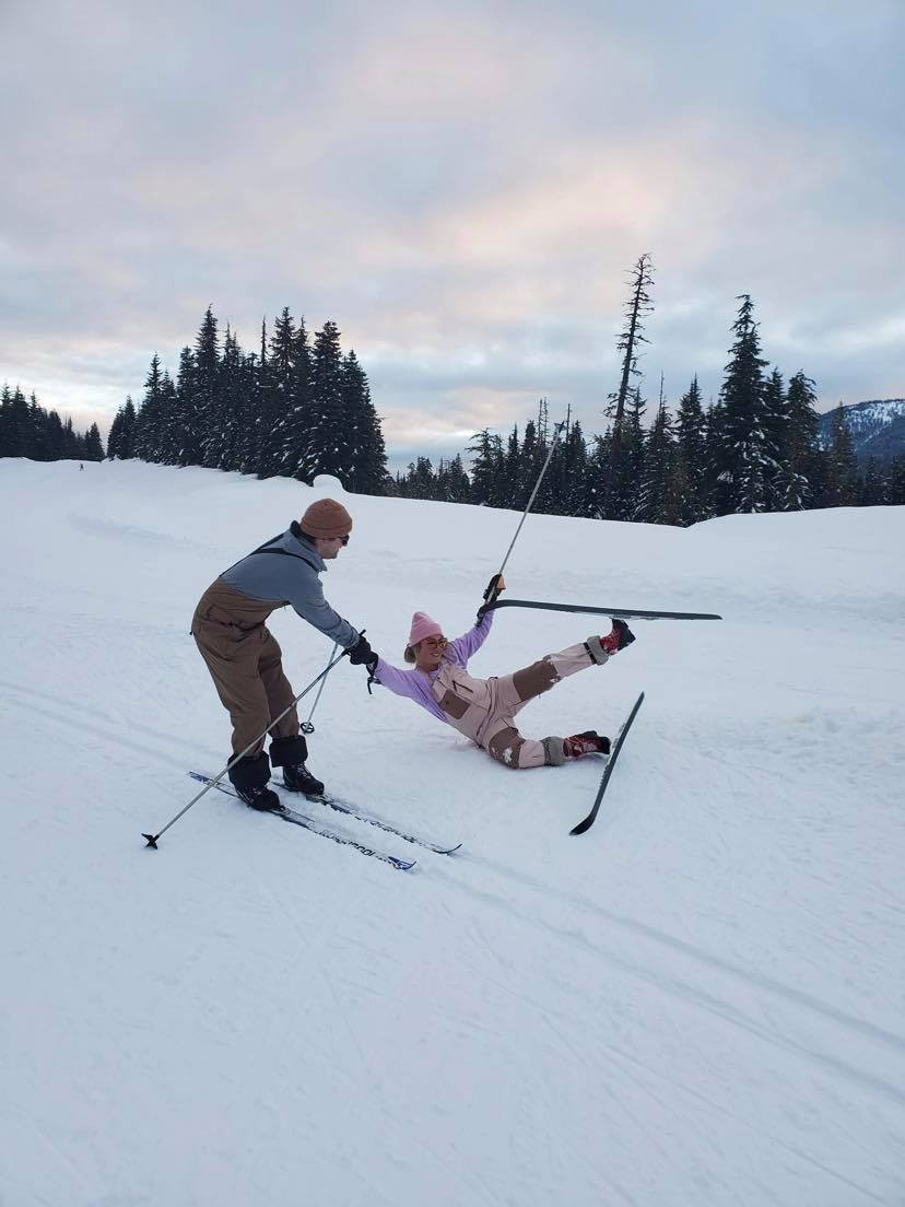 Boy helping girl, girl fell with skis, beautiful sky at Callaghan
