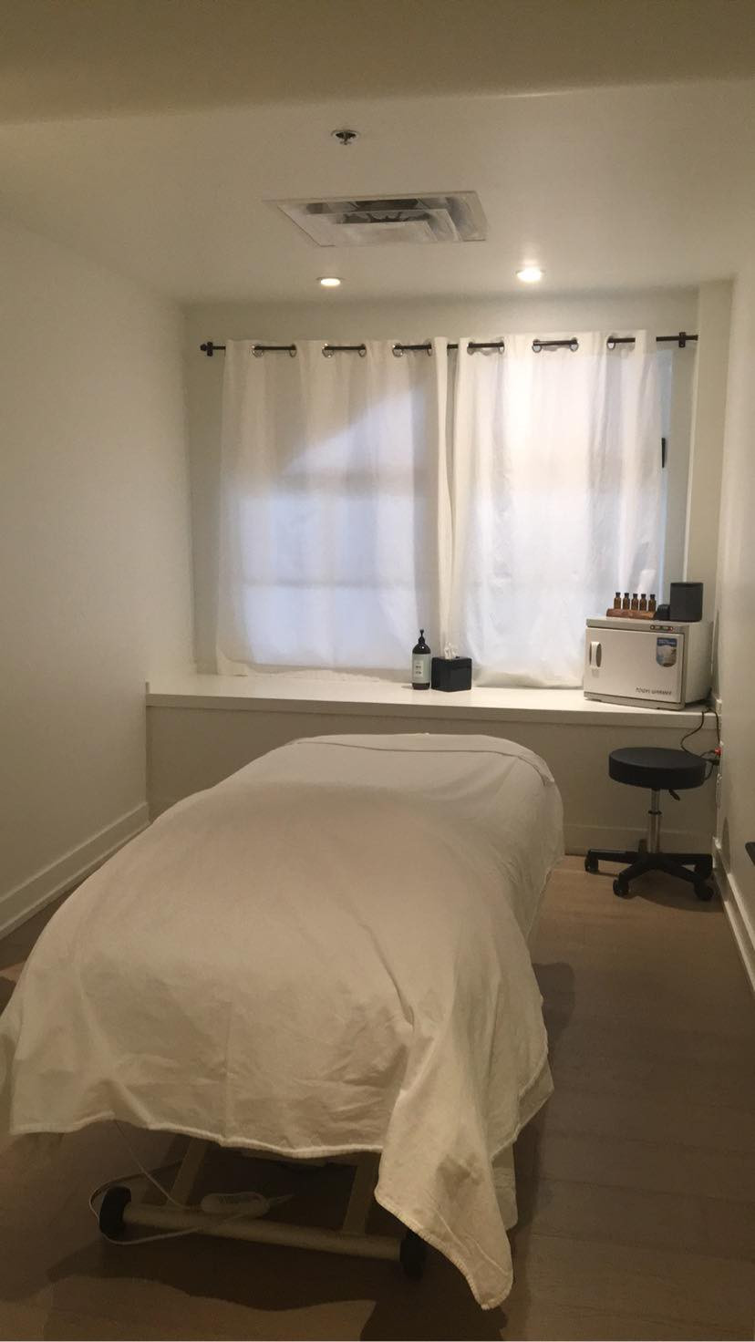Treatment room at spa, with window, bed, and hot towel cabnet