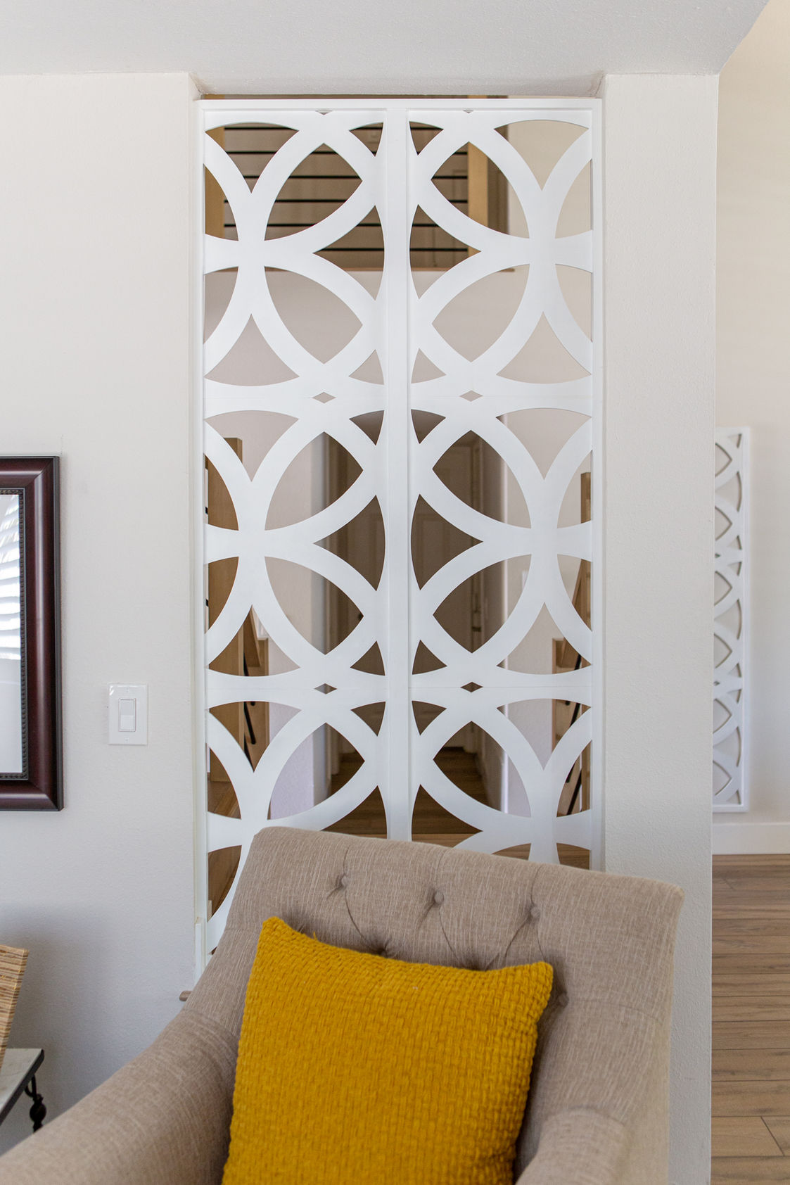 White geometric lattice screen behind a tufted chair.