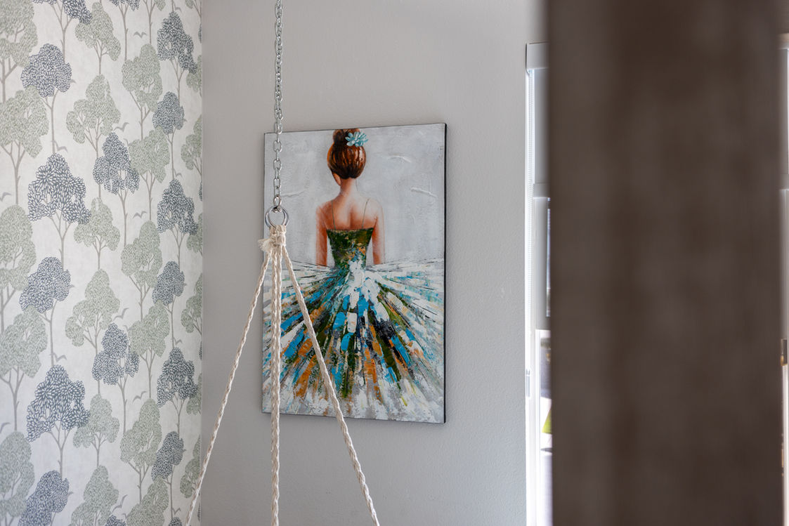Painting of a ballerina on a wall beside tree wallpaper