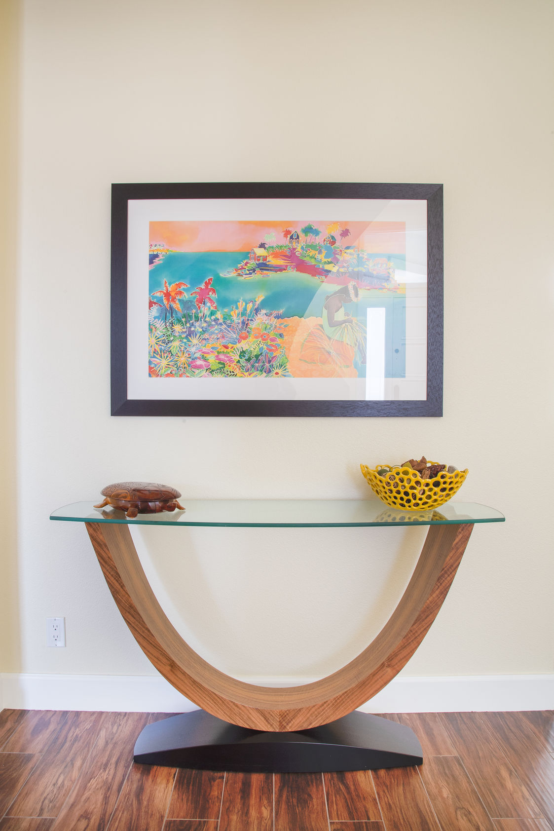 Modern curved wood console table with artwork above it.