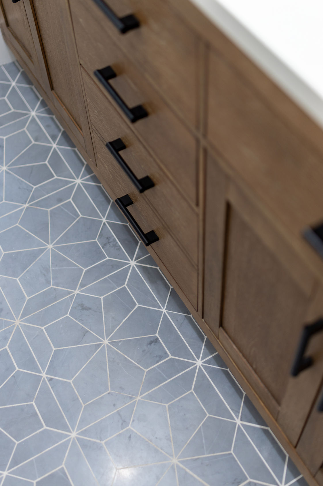 Blue geometric star patterned tile floor next to wood vanity