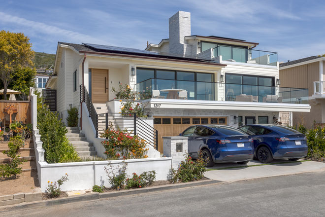 Modern white house with solar panels and blue electric car