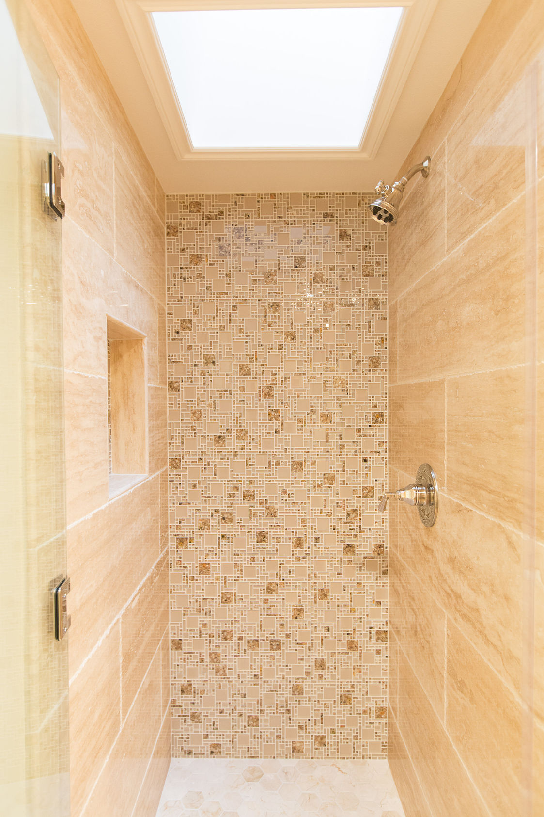 Modern walk-in shower with stone tile and skylight
