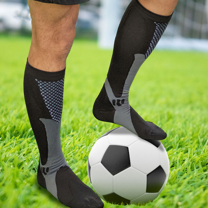 Meias de compressão pretas para futebol em campo gramado.