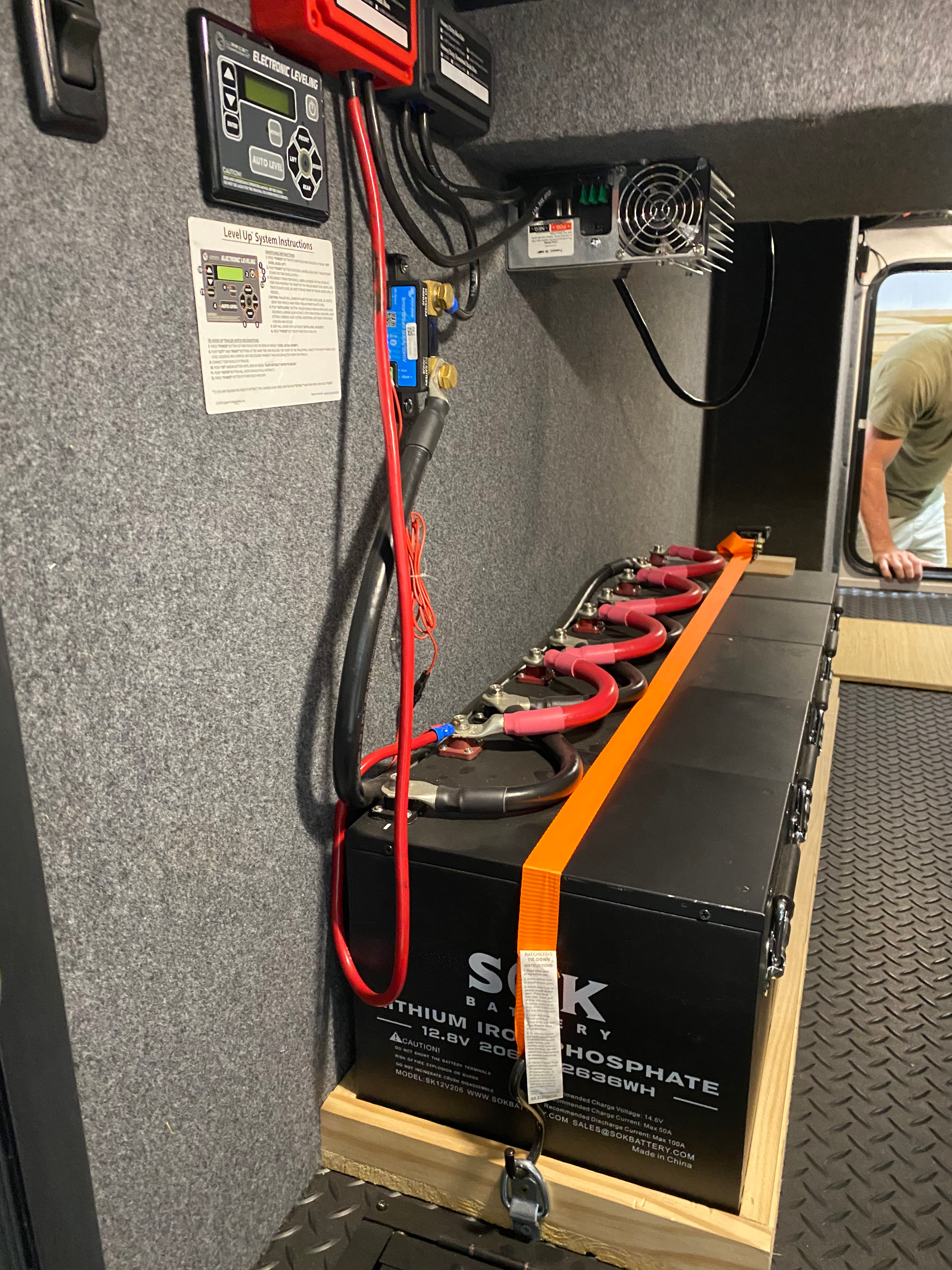 RV battery compartment with connecting cables and an orange hold-down strap
