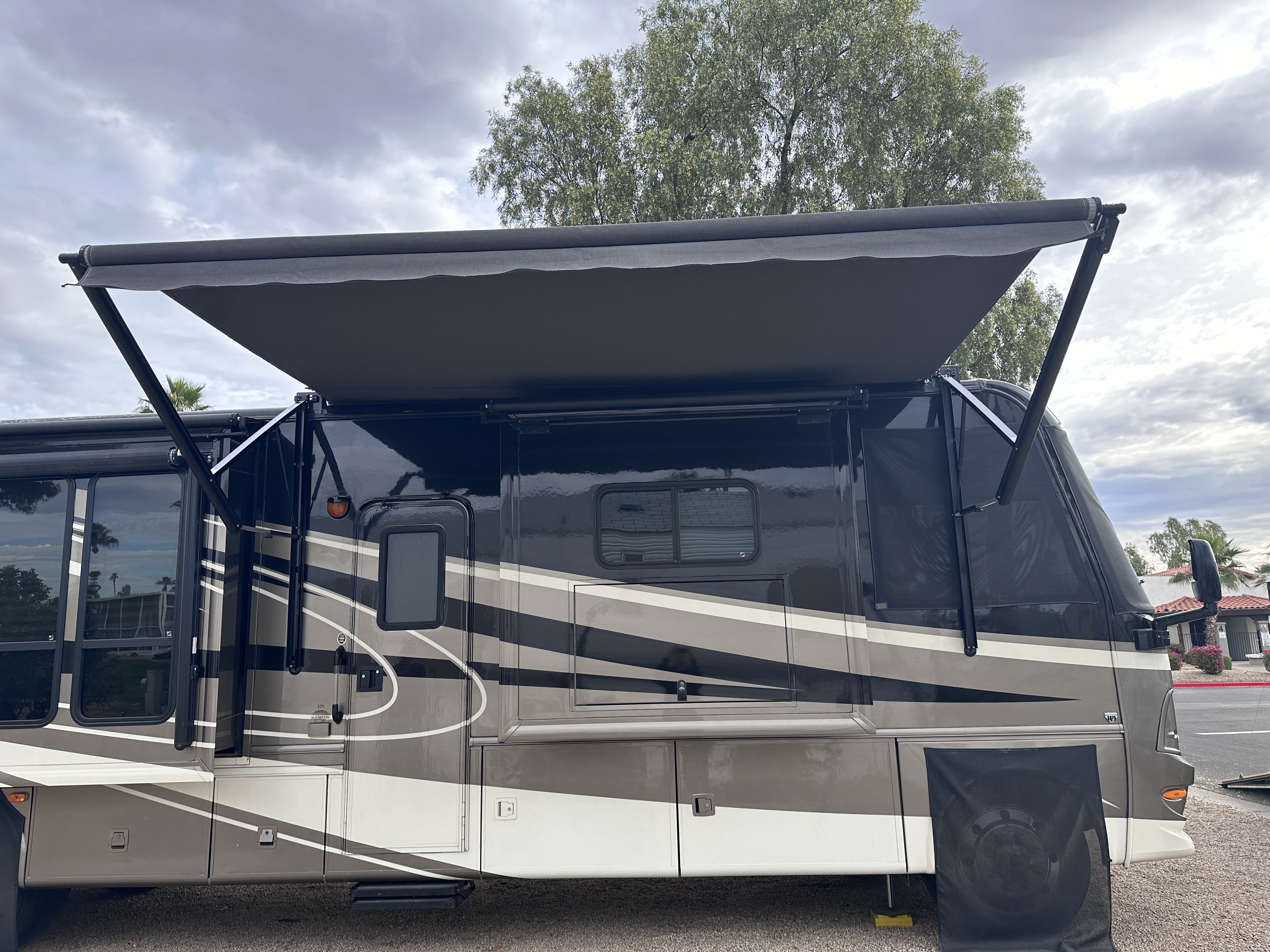 Class A motorhome parked outdoors with its side awning extended