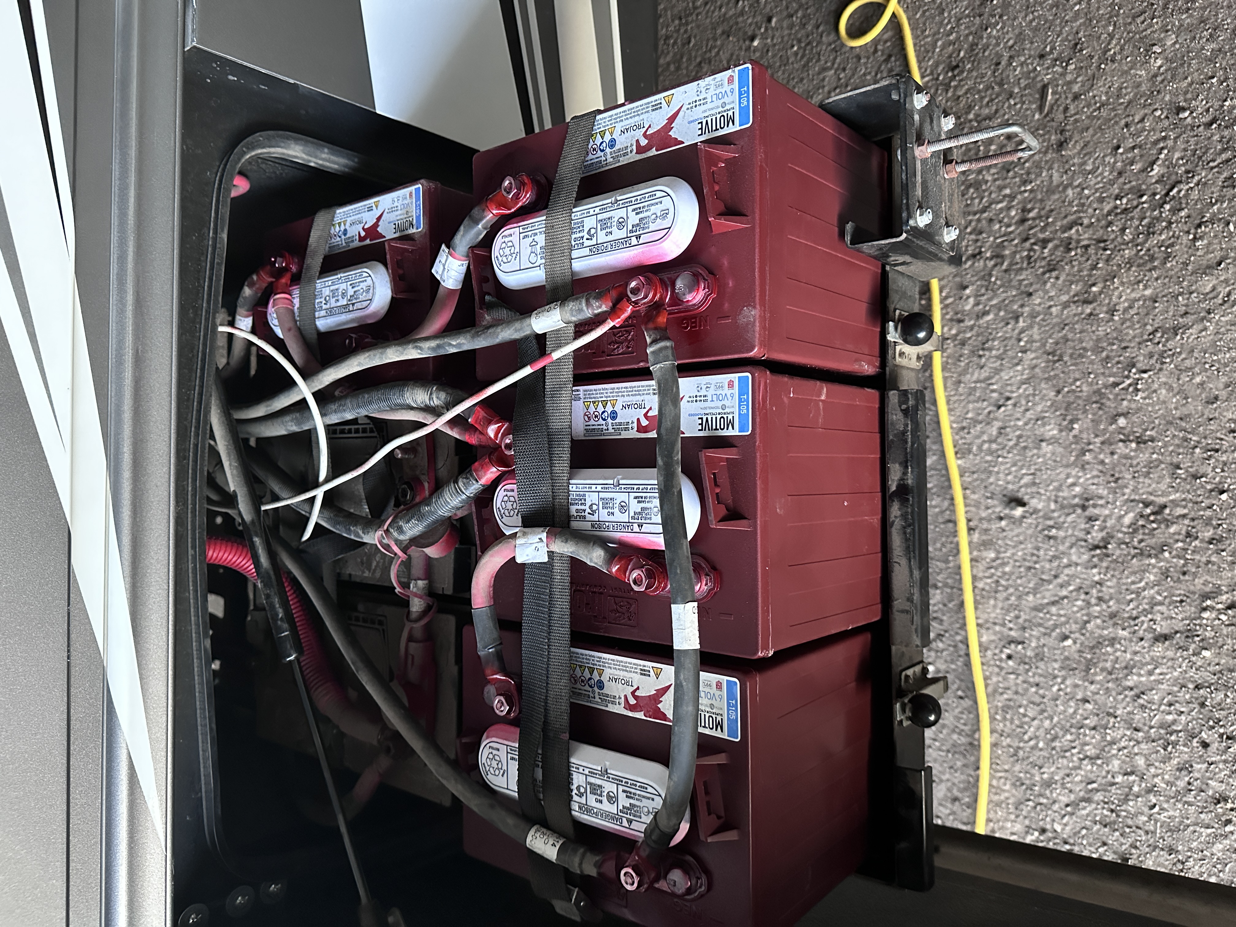 RV house-battery bank with red batteries, connecting cables and hold-down straps