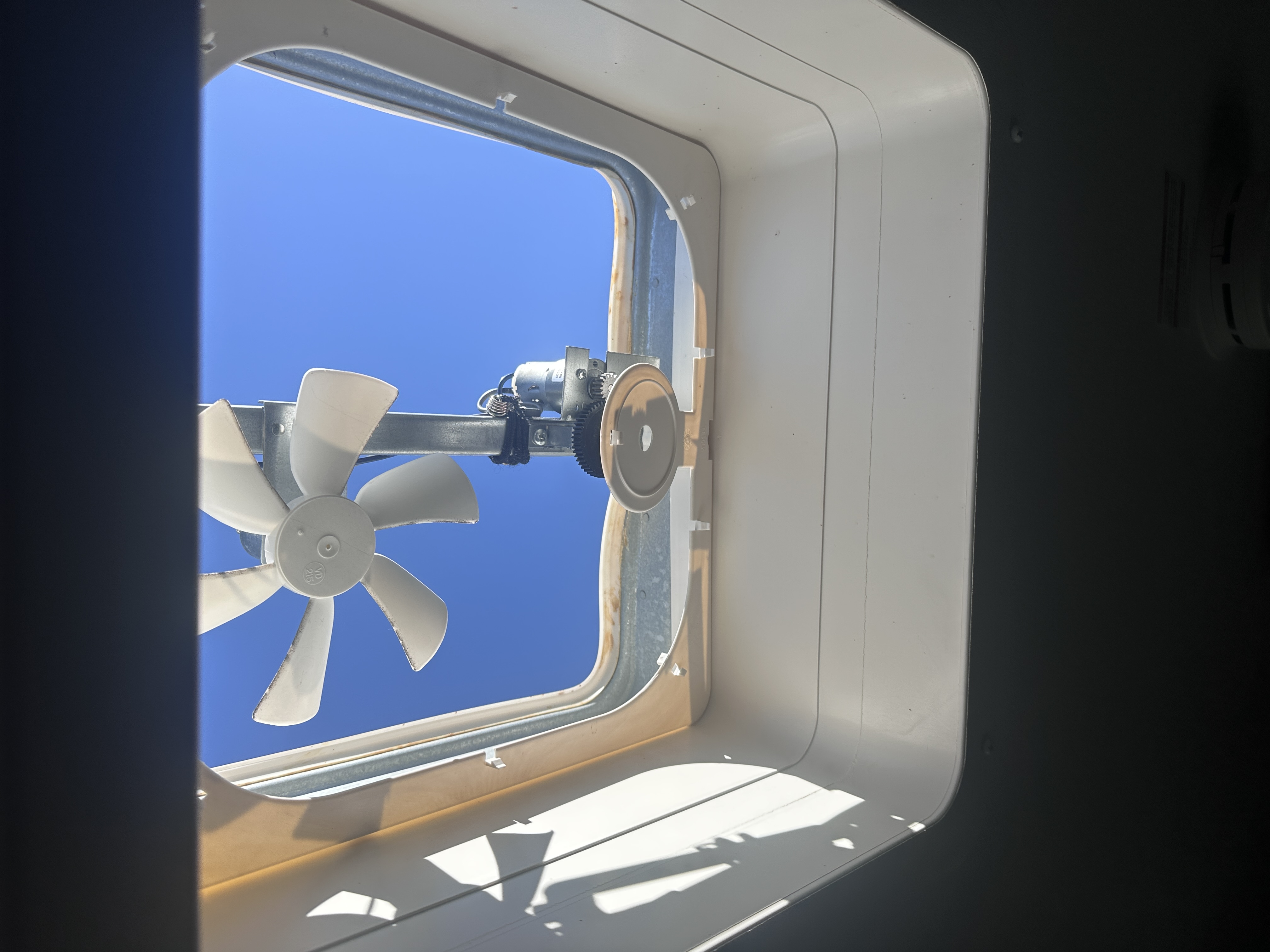 RV roof vent opening with fan blades and motor assembly viewed from inside the coach