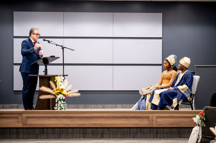 Person speaking at podium, audience in traditional attire.