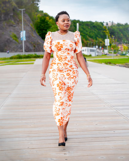 Woman in floral dress walking on boardwalk.