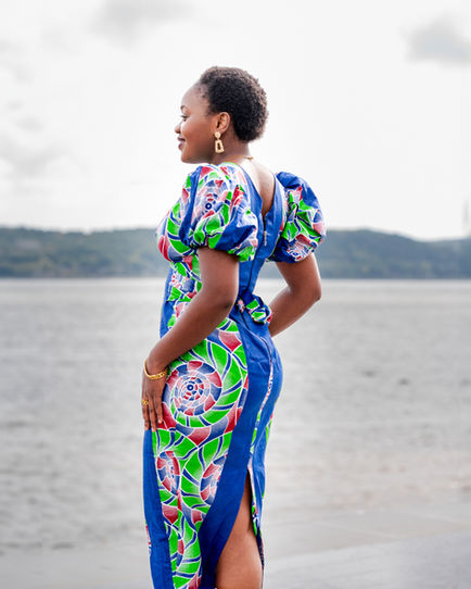 Woman in colorful dress standing by a lake.