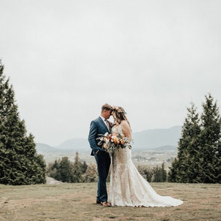 A picture of the bride and groom close to each other on a hill