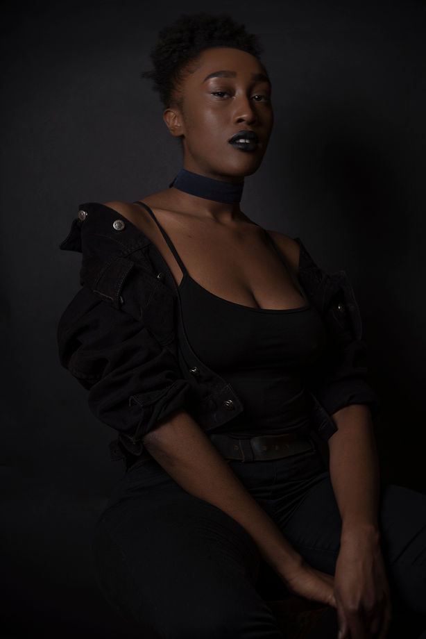 Photo couleur, plan américain. Photographie de portrait, esprit photographie édito de mode d'une femme vêtue de noir sur fond noir.