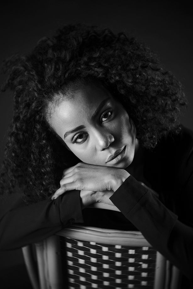 Photographie professionnelle en noir et blanc, plan poitrine. Portrait photo d'une femme sur fond noir.