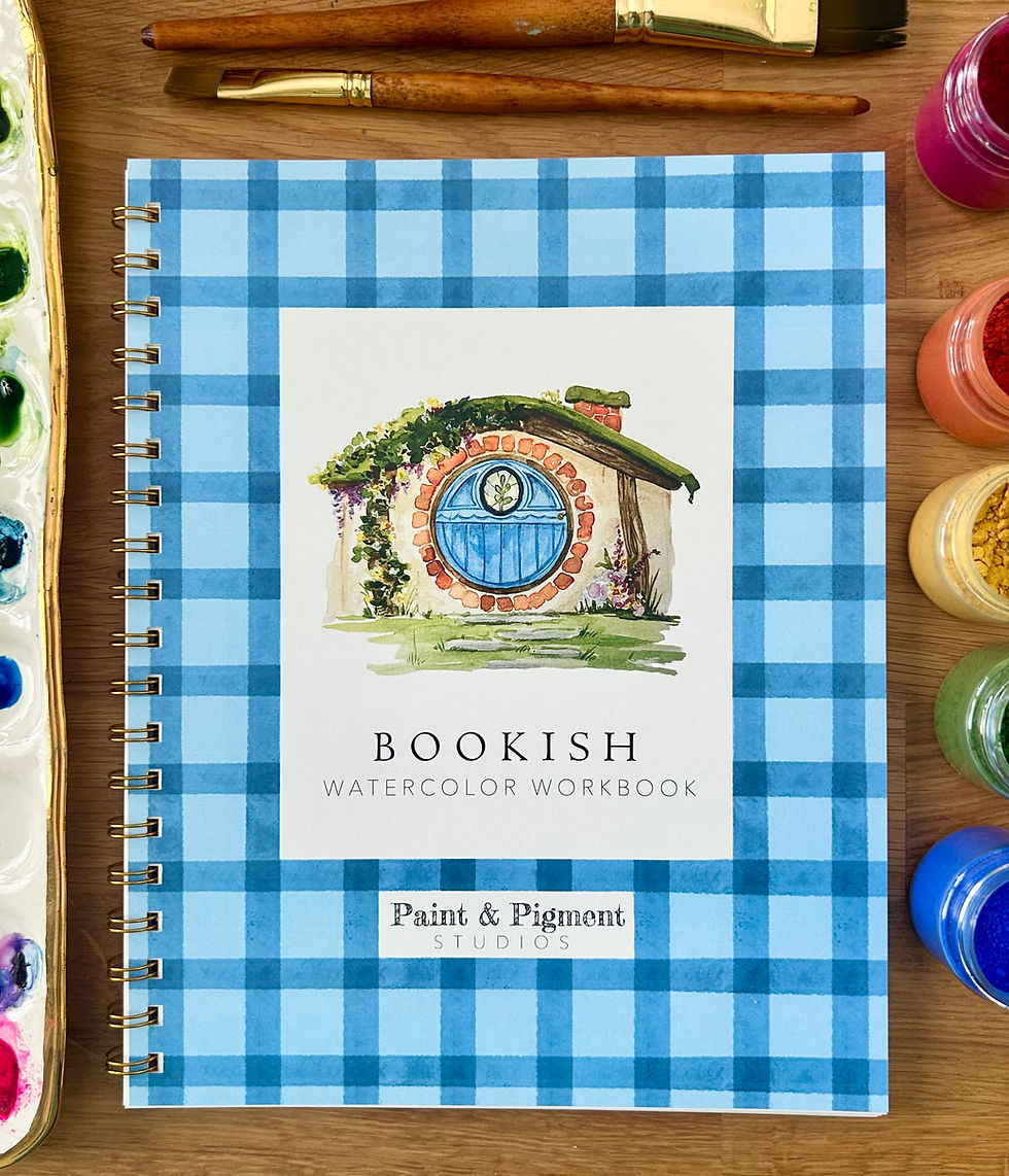Book with blue gingham edges depicting a hobbit house with a blue door is sitting on a table with rainbow paints and brushes.
