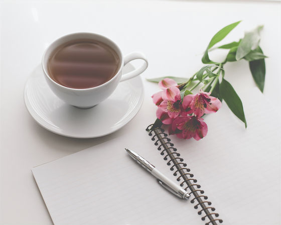 A blank journal, a cup of tea and flowers