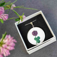 Obesek deteljice izdelan z bombažnimi in kovinskimi nitmi na ramiji.