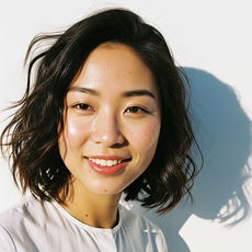 Smiling woman in white shirt against a white wall. TOUSSELLED.COM