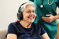 senior woman, wearing dark blue with black headphones doing music therapy and is happy. Sh
