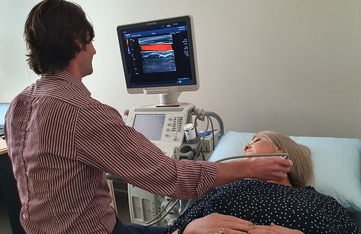 One of The Vascular Centre ultrasonographers scanning a patient's carotid arteries with the ultrasound machine in view.