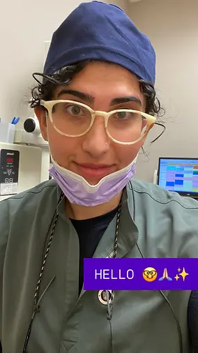 Selfie portrait of Dr. Noor N. Ay Toghlo, smiling kind warm gentle dentist, wearing a scrubs figs in a professional setting.