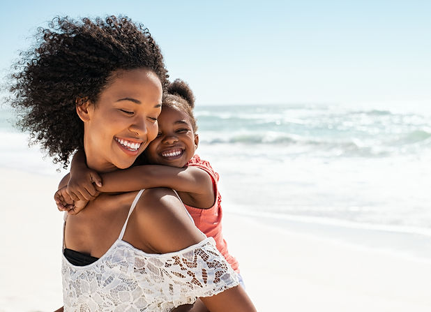 Smiling young black mother and beautiful daughter having fun on the beach with copy space