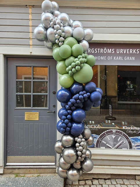 Organisk ballongbåge till entrén av butik i silver, grönt och blått 