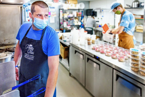 Man in black apron prepping food in a commercial kitchen