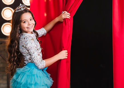 smiling-girl-wearing-crown-opening-red-curtain (1).jpg
