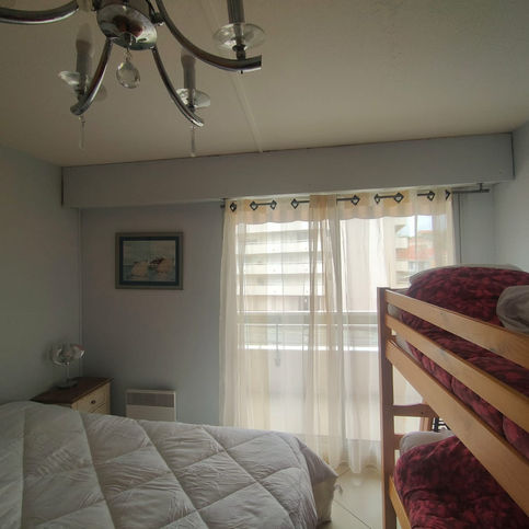 Chambre sur-mesure à Arcachon avec meuble intégré, suspension en fibres naturelles, sol effet chêne clair et ambiance sable et lin – projet de décoration intérieure pour location saisonnière.