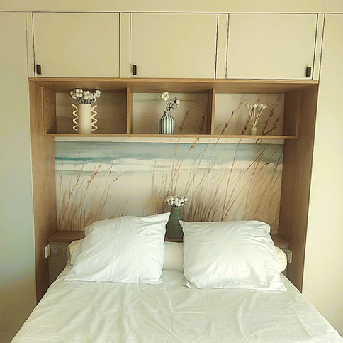 Chambre sur-mesure à Arcachon avec meuble intégré, suspension en fibres naturelles, sol effet chêne clair et ambiance sable et lin – projet de décoration intérieure pour location saisonnière.
